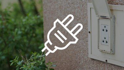 A white plug icon overlaid against the outside of a house with an electrical outlet.