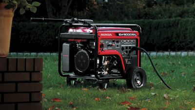 A Honda generator sits outside on a residential lawn.  