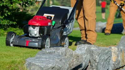 Closeup of Honda mower being pushed by a landscaper on a premium residential property.  