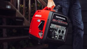 Gros plan d’une personne transportant une génératrice Honda portable.  