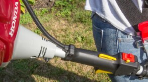 A close-up image of a person using a Honda handheld tool.  