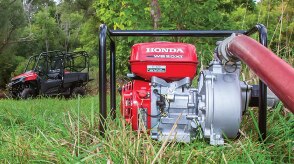 Medium wide view of a Honda pump on in a field. In the background, there’s an ATV. 